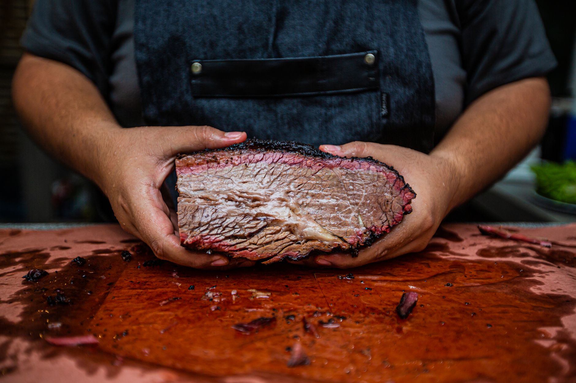 A pitmaster holding a freshly smoked, halved brisket